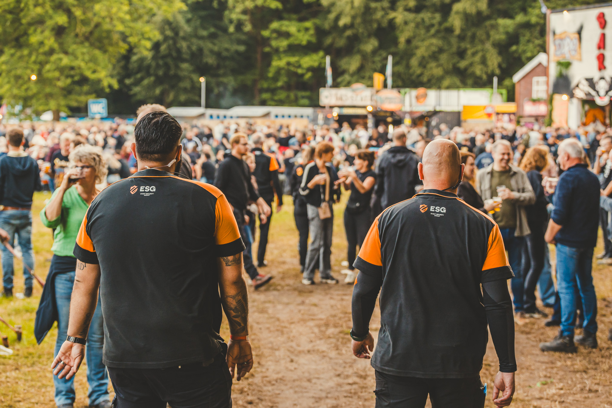 Twee ESG-beveiligers lopen tussen de bezoekers op een festivalterrein