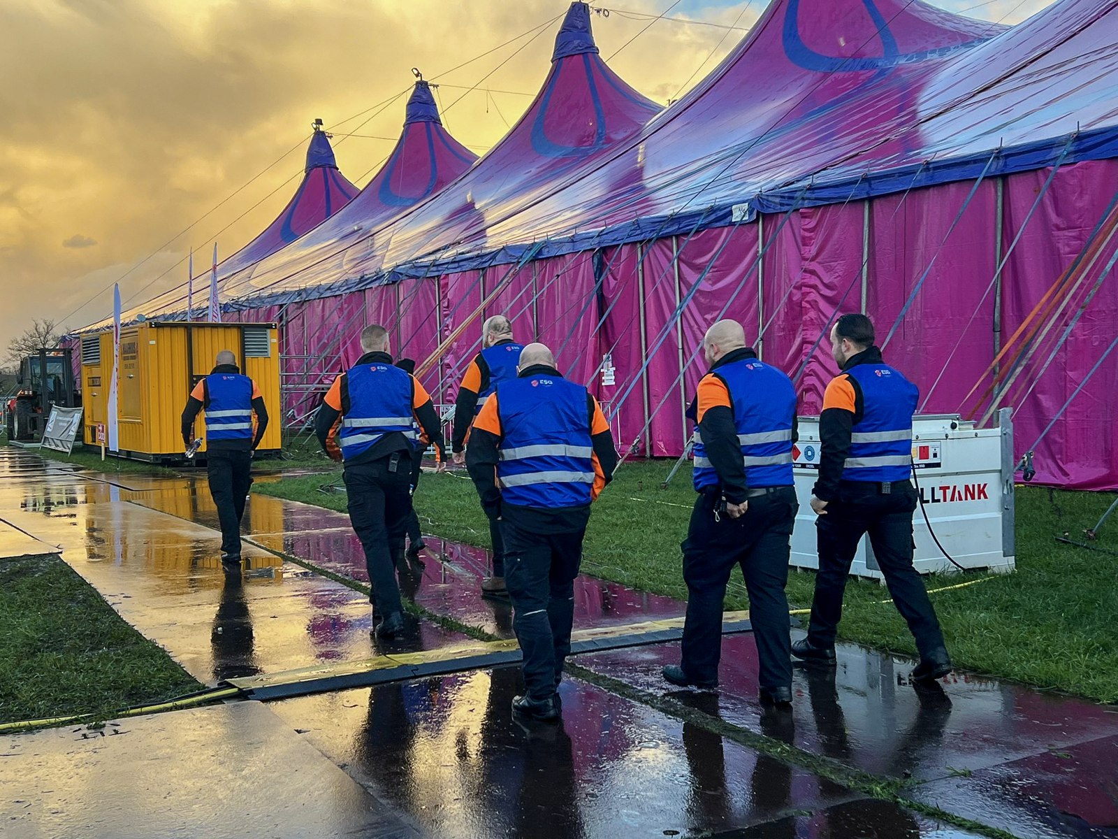 ESG-medewerkers lopen langs een grote roze feesttent op een evenemententerrein