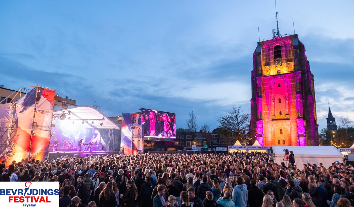 Festivalpubliek, podium en de verlichte Oldehove bij Bevrijdingsfestival Fryslân